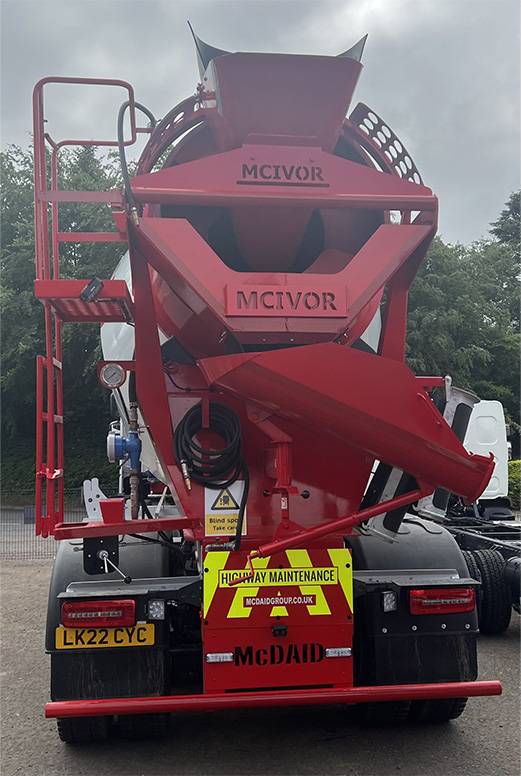 Rear view of heavy-duty mixer truck with rotating drum in action